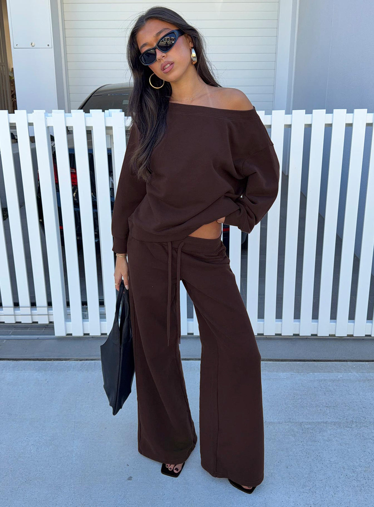 Showcasing the Wellness Off The Shoulder Jumper Brown in women's jumpers with long length and oversized fit front view of model wearing Princess Polly
