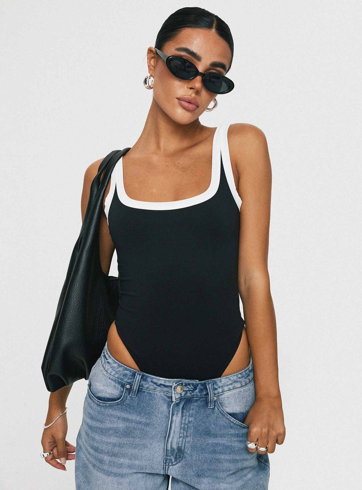 side view of model wearing Princess Polly Astrea Bodysuit Black / White Sleeveless Bodysuit 