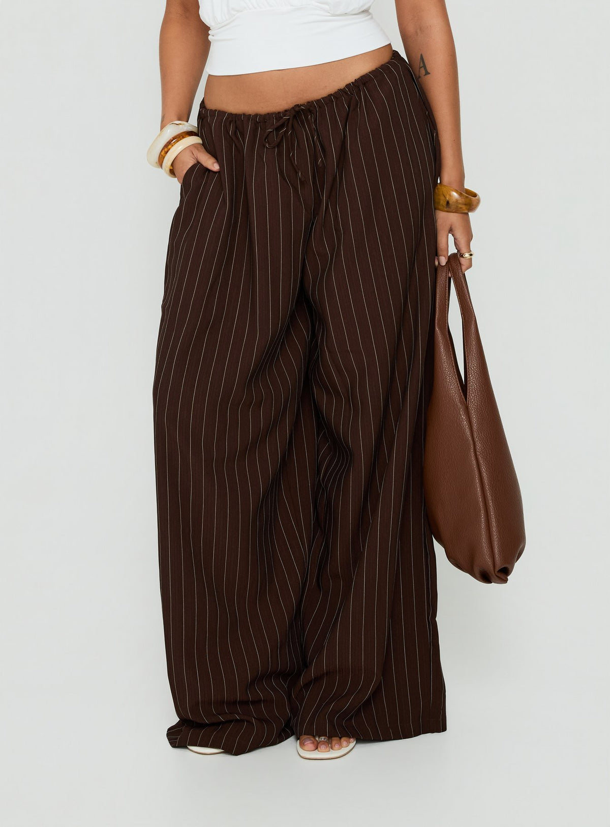 Showcasing the Bungala Oversized Relaxed Pants Brown Pinstripe womens-regular-pants with mid-rise front view of model wearing Princess Polly