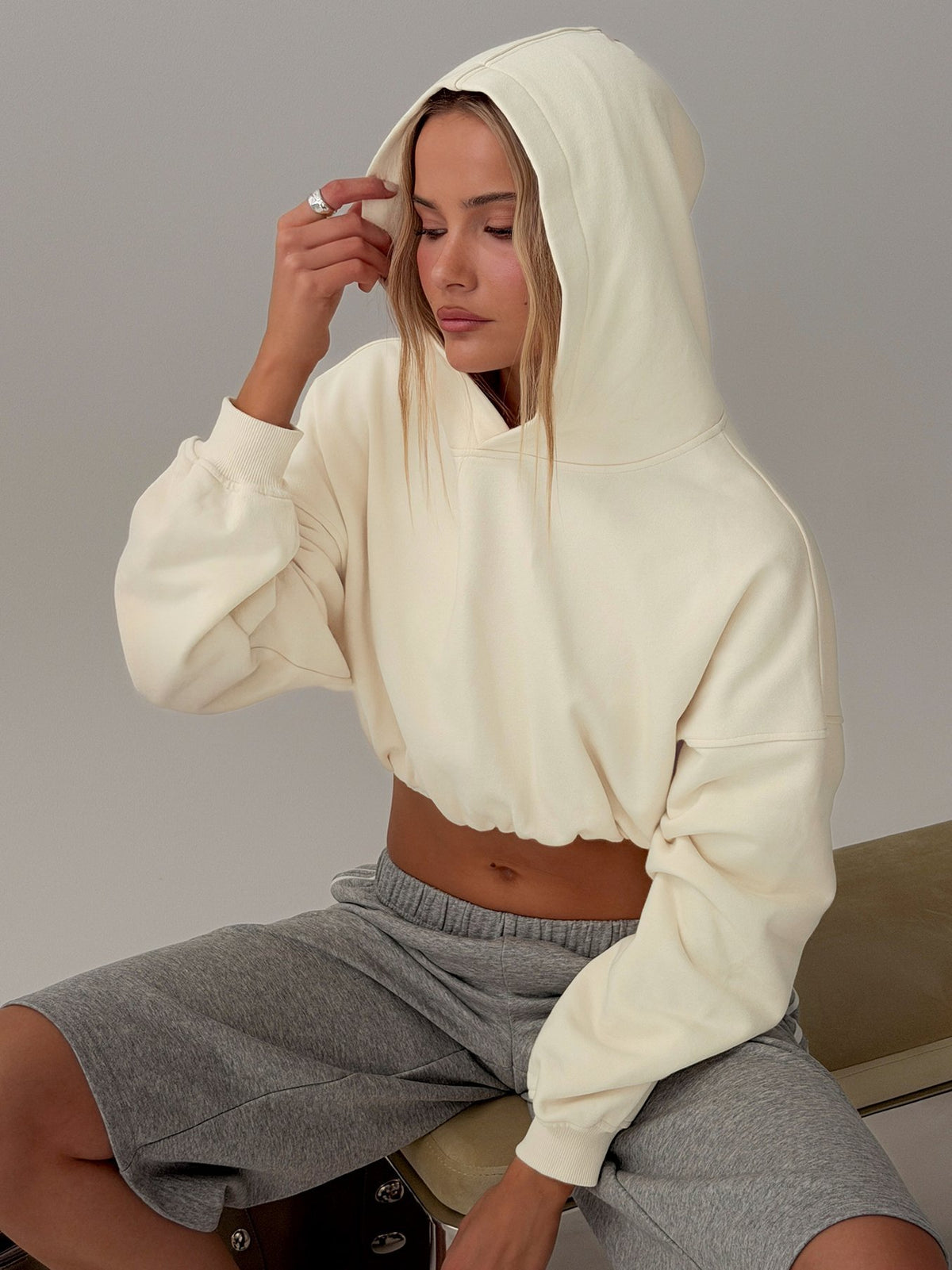 Showcasing the Mayse Bubble Hem Cropped Hoodie Cream womens jumpers in short length side view of model wearing Princess Polly