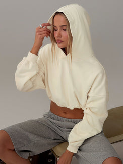 Showcasing the Mayse Bubble Hem Cropped Hoodie Cream womens jumpers in short length side view of model wearing Princess Polly
