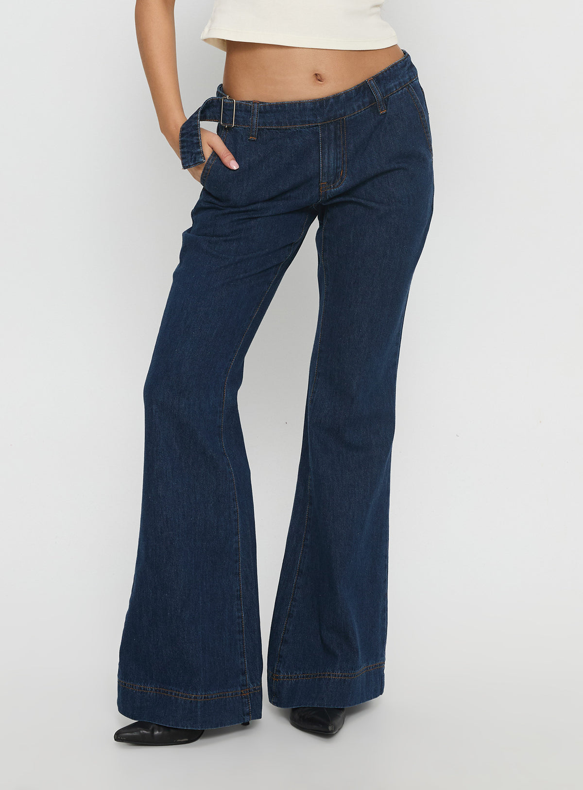 side view of model wearing Princess Polly Acapulco Low Rise Flare Jeans Dark Blue Wash Low Rise Jeans Jeans 