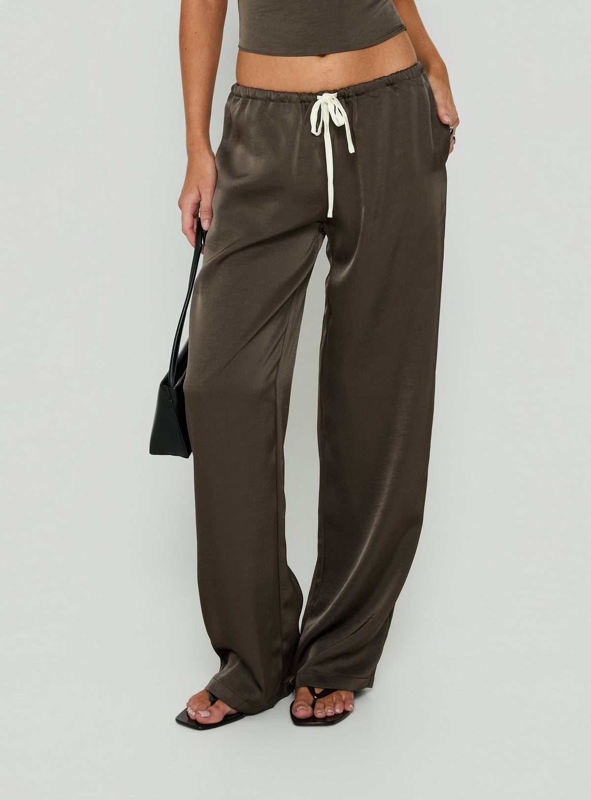 Featuring the Dialled Up Tie Waist Satin Pants Mocha in womens regular wide-leg silhouette with mid-rise belt side view of model wearing Princess Polly