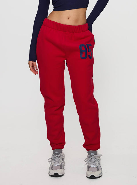 Crafted from red fleece, U of A Sweatpants in womens regular pants with mid-rise and graphic print, front view of model wearing