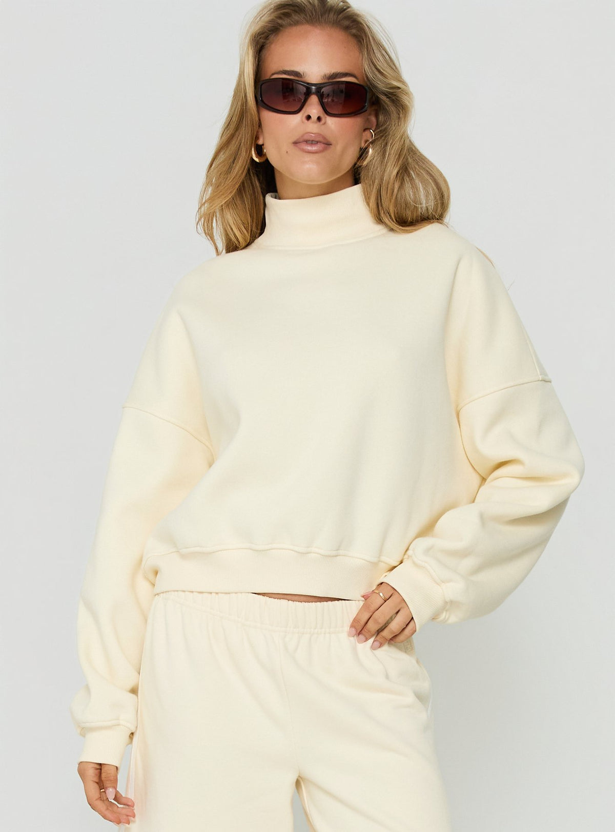 Featuring the Anyya Funnel Neck Crew Jumper Cream womens short oversized jumper side view of model wearing Princess Polly