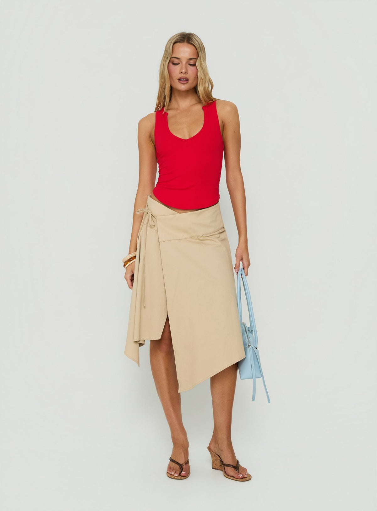 Discover the Ellainah Asymmetrical Wrap Midi Skirt Concrete in tan front view of model wearing Princess Polly