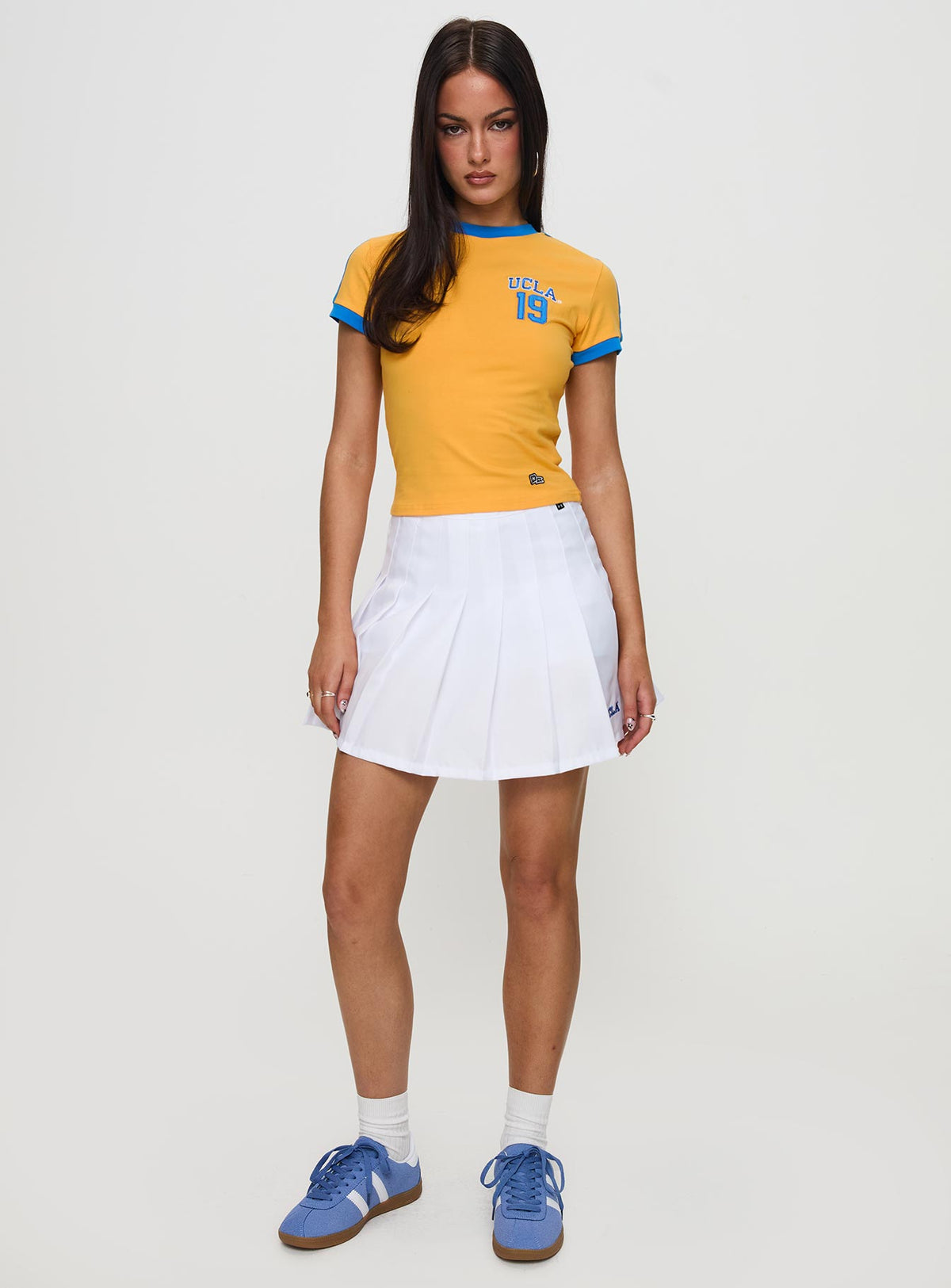   side view of model wearing Princess Polly UCLA Tennis Skort White Skirts 
