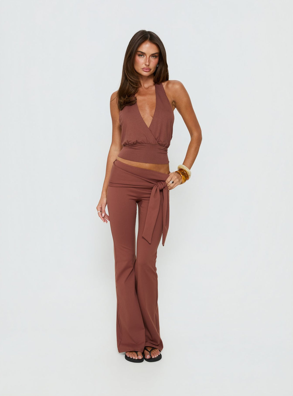 Showcasing the Daily Define Tie Waist Pants Brown in womens regular pants with high-rise and wide-leg styling front view of model wearing Princess Polly