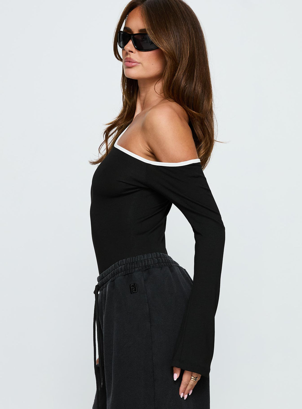 side view of model wearing Princess Polly Andrielle One Shoulder Long Sleeve Bodysuit Black / White Long Sleeve Tops Bodysuit 