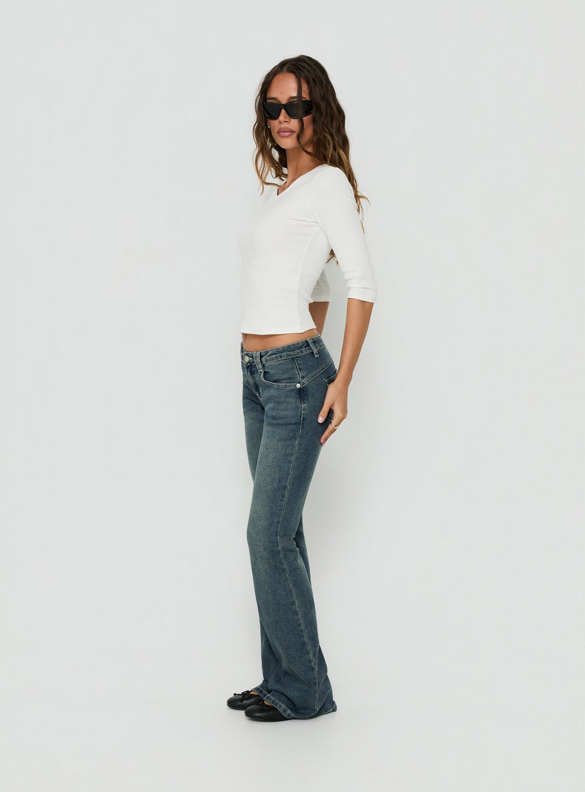 Presenting the Clynee Ultra Low Rise Bootleg Jeans Dirty Blue in womens-jeans with low-rise waist side view of model wearing Princess Polly