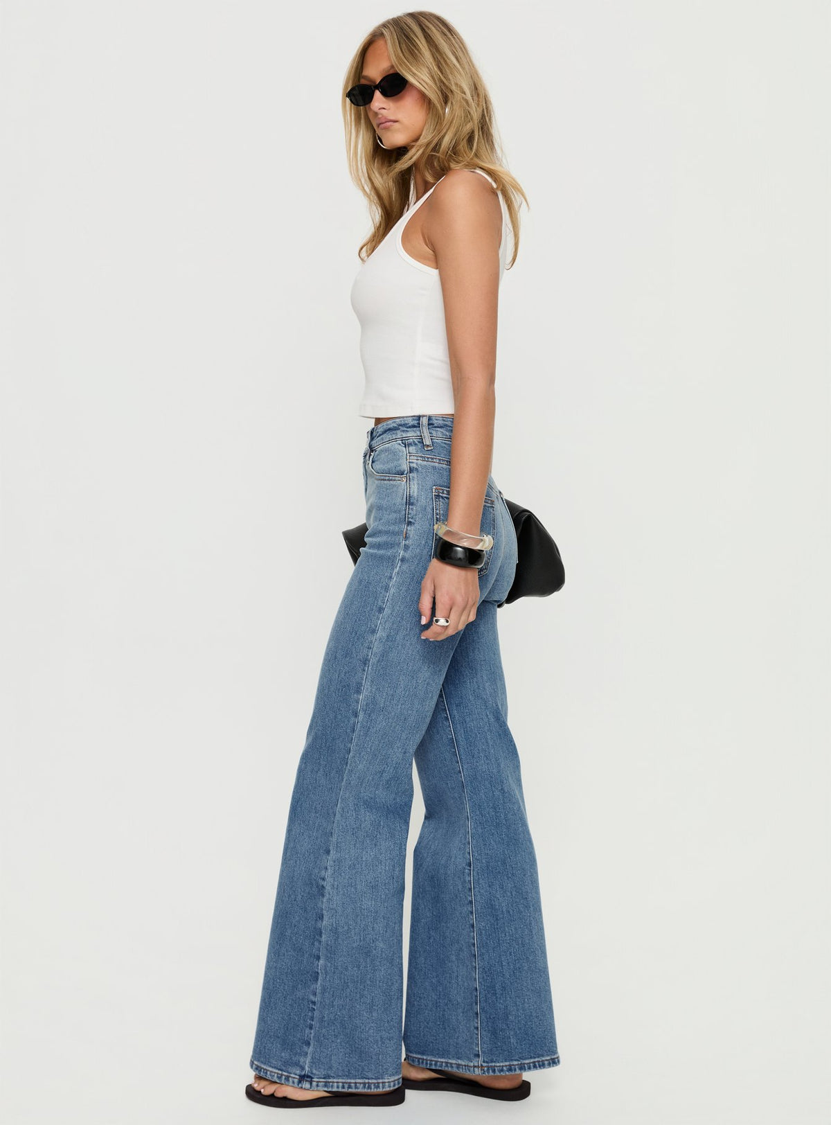 side view of model wearing Princess Polly Thearlie High Rise Flared Jeans Mid Blue Wash High Rise Jeans Jeans 