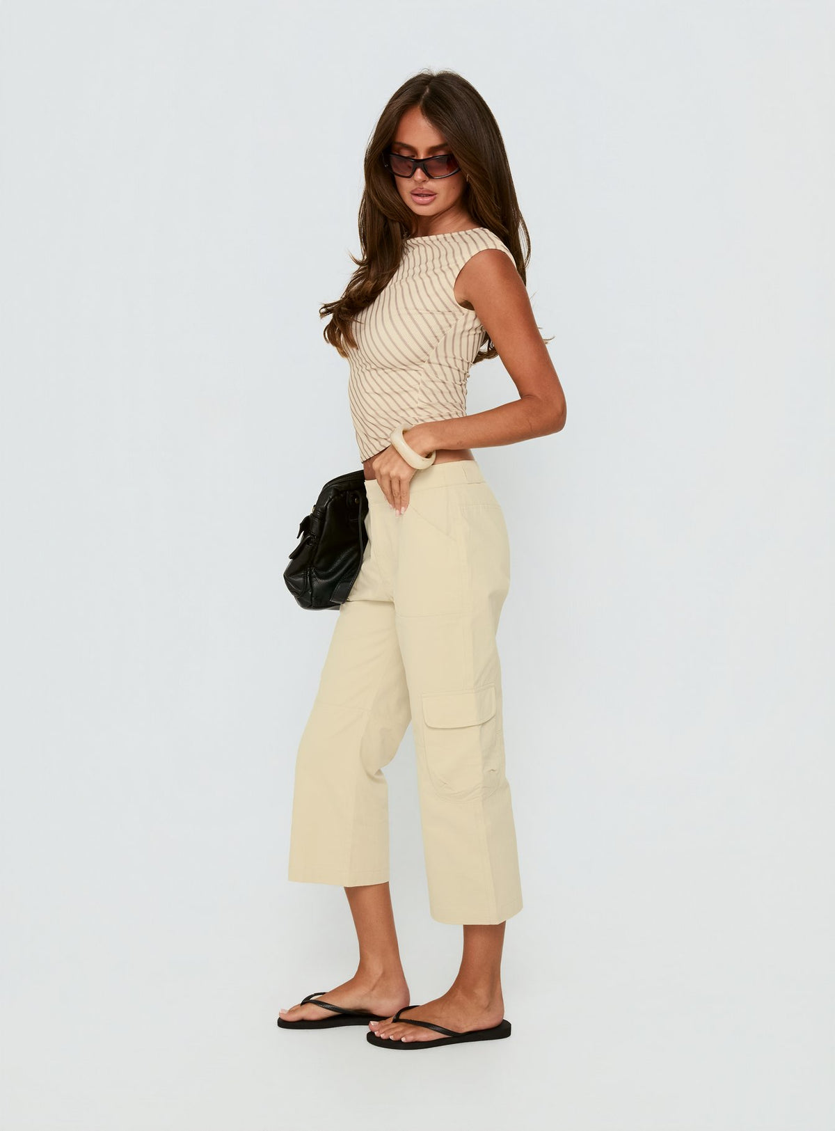 Displaying Indee Cropped Cargo Pants Beige Petite womens-regular-pants with high-rise side view of model wearing Princess Polly