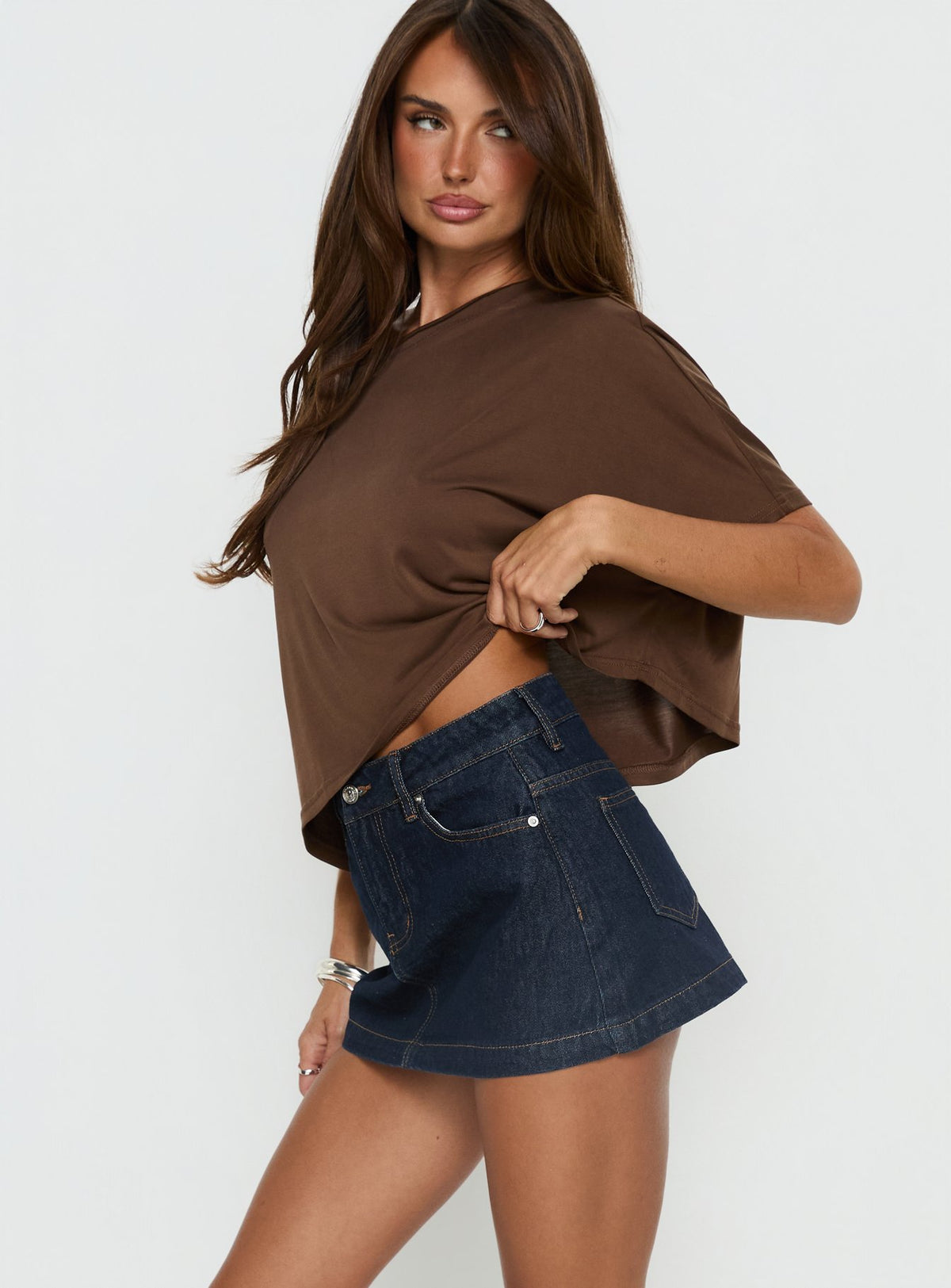   side view of model wearing Princess Polly Nicolina Low Rise Denim Mini Skirt Raw Denim Mini Skirts Skirts 