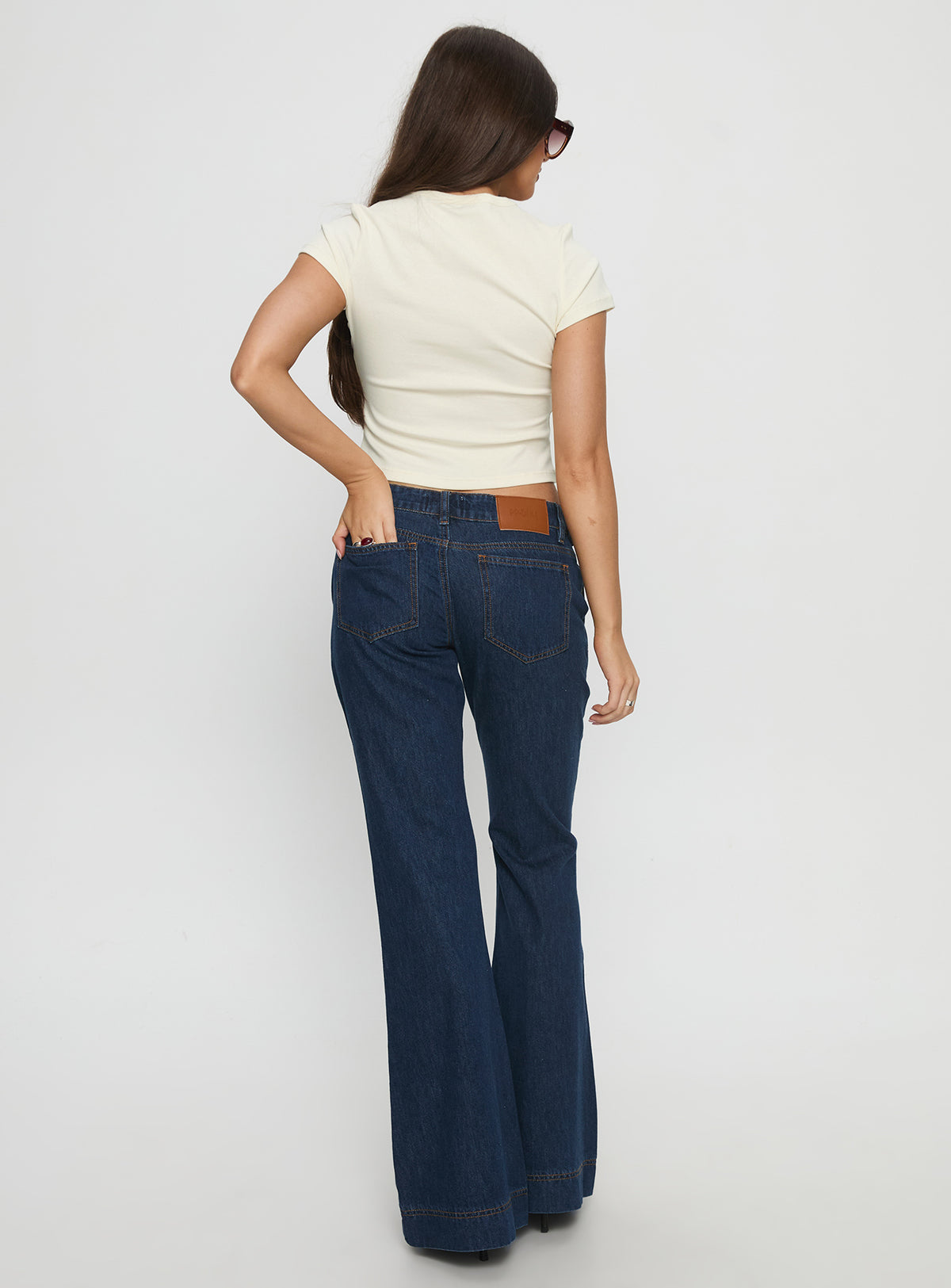 back view of model wearing Princess Polly Acapulco Low Rise Flare Jeans Dark Blue Wash Low Rise Jeans Jeans 
