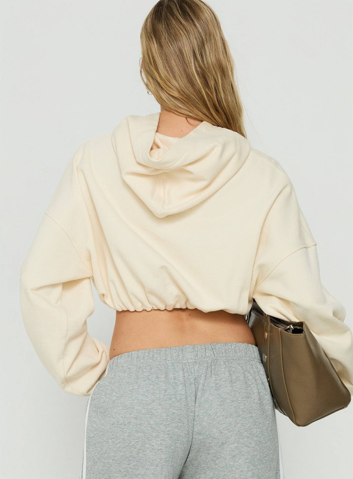 Displaying the Mayse Bubble Hem Cropped Hoodie Cream womens jumpers in short length back view of model wearing Princess Polly