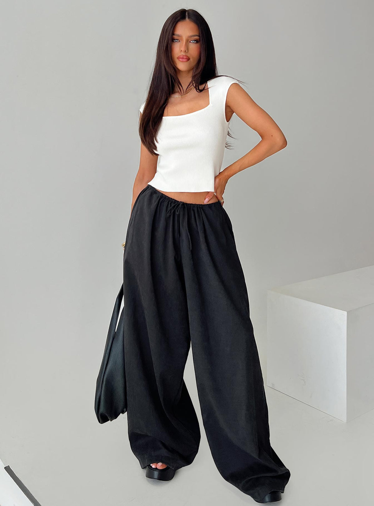Showcasing the Bungala Oversized Relaxed Pants Black Tall wide-leg womens regular pants in mid-rise front view of model wearing Princess Polly