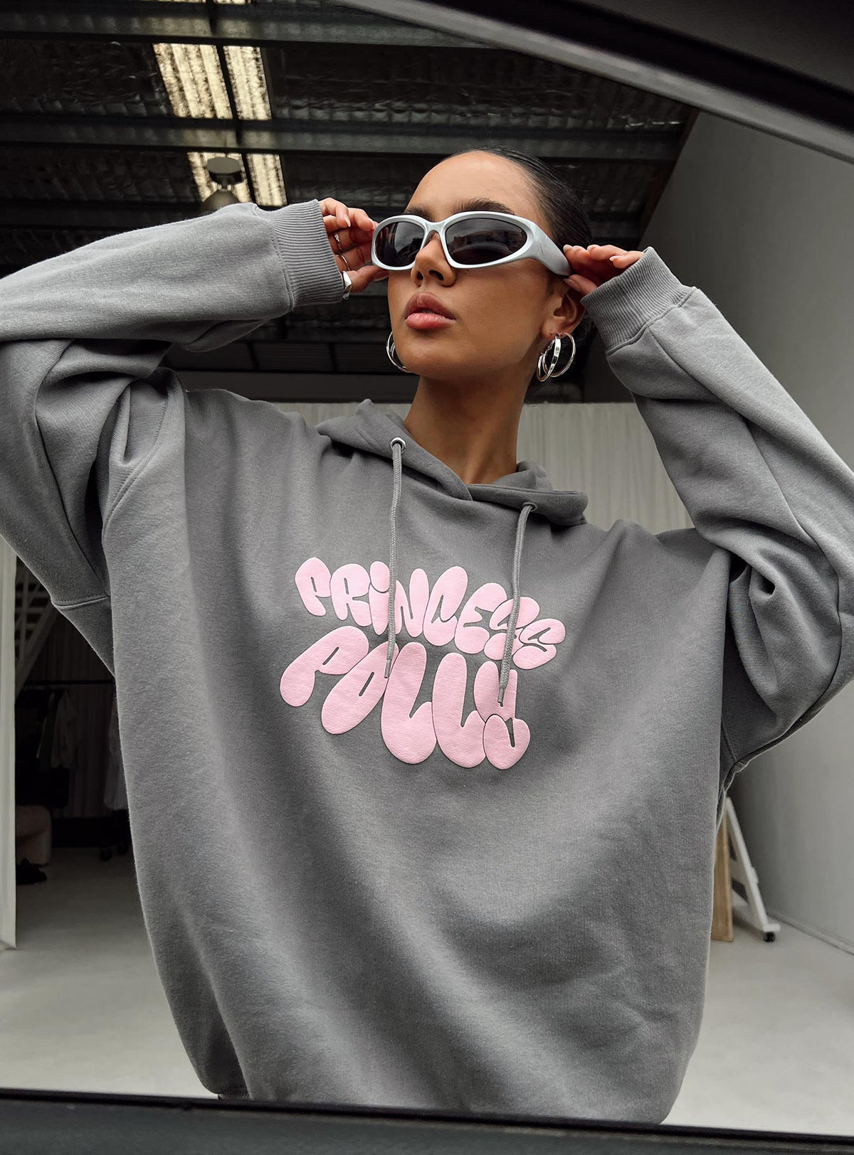 side view of model wearing Princess Polly Princess Polly Hooded Sweatshirt Bubble Text Charcoal / Light Pink Longline Jumpers Jumpers 